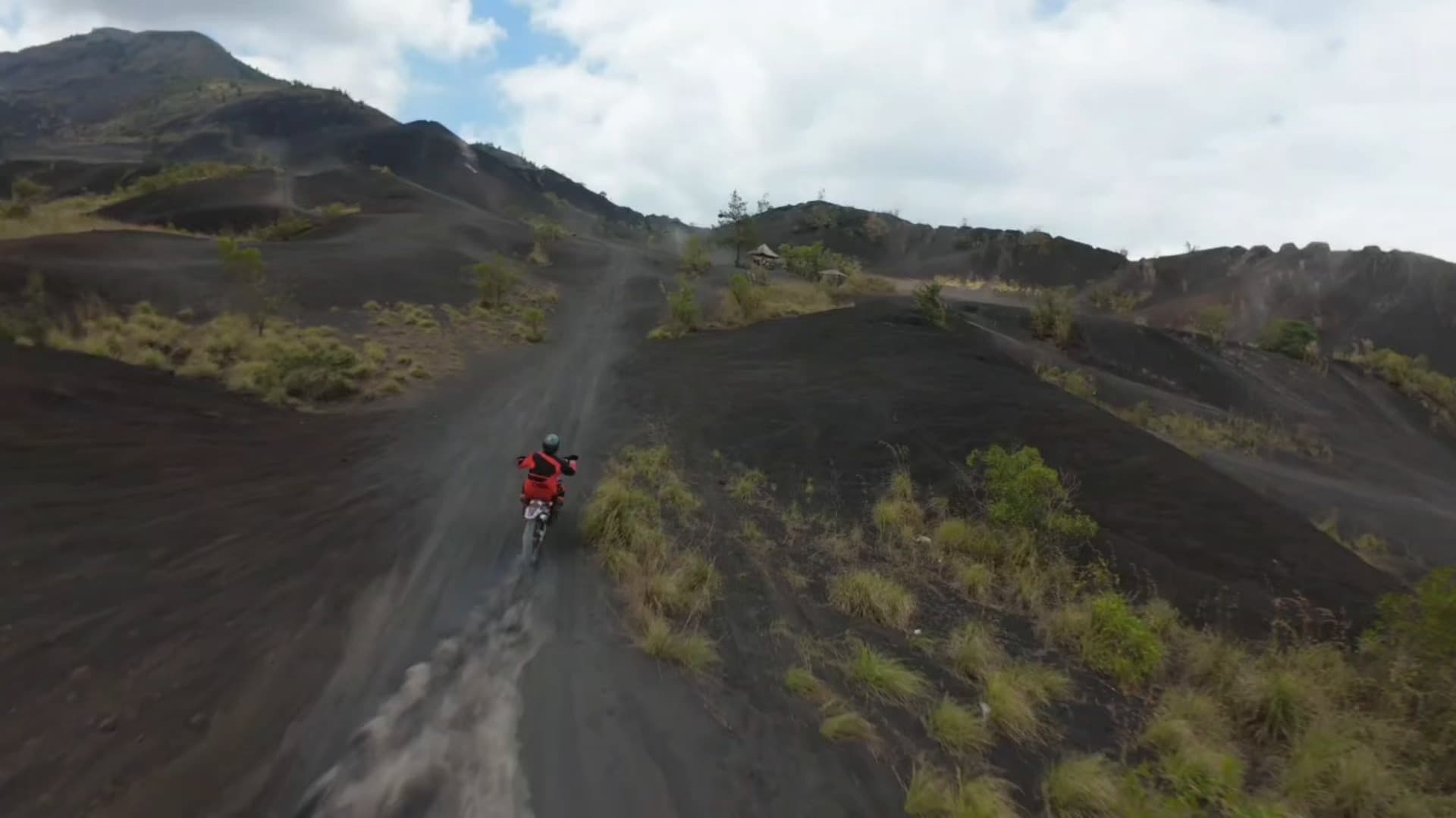 A dirt bike rider on the black ash track below Mount Batur, seen from the air