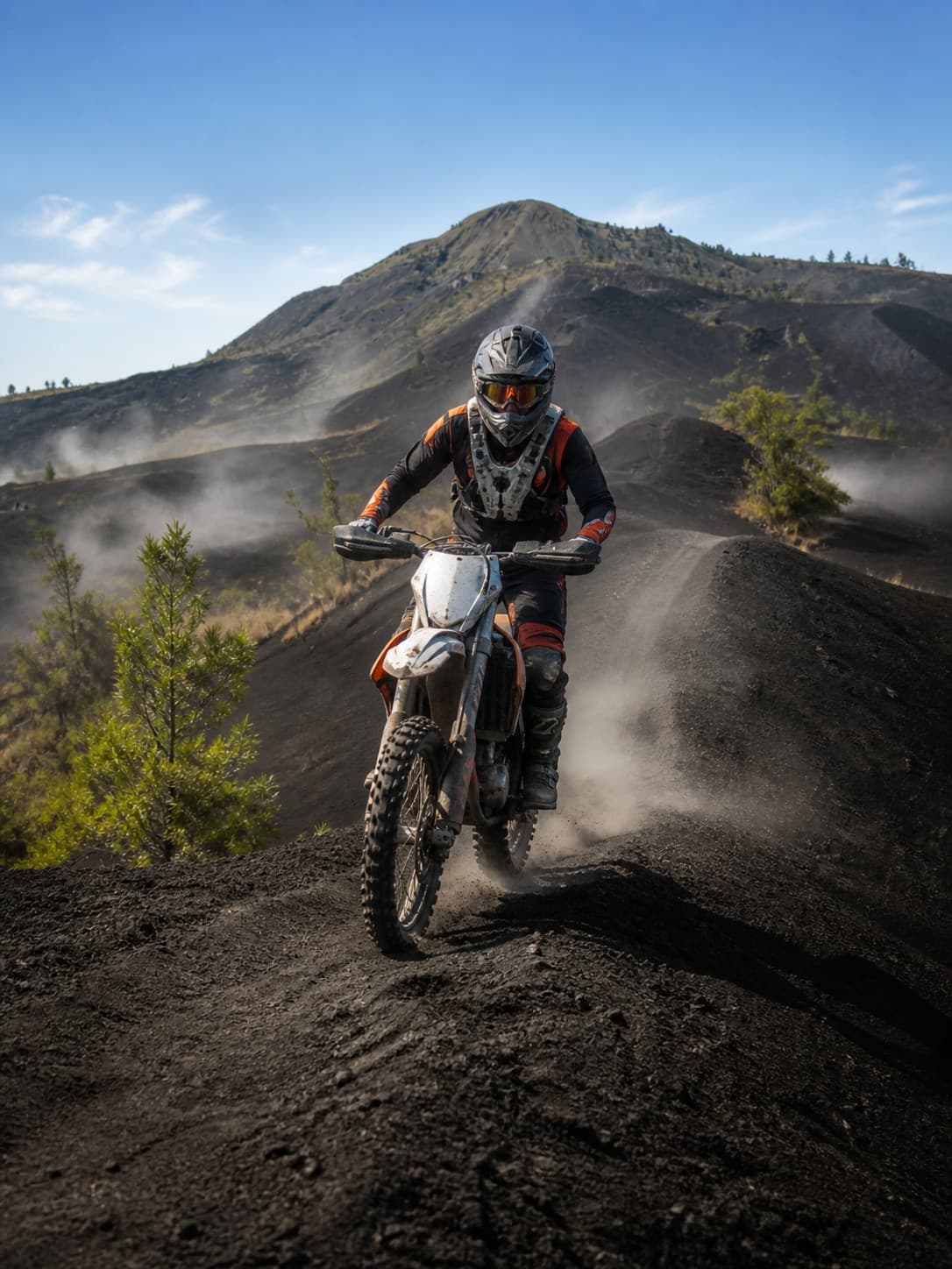 A rider in full body armour on a 250cc trail bike, crossing the black lava field below Mount Batur