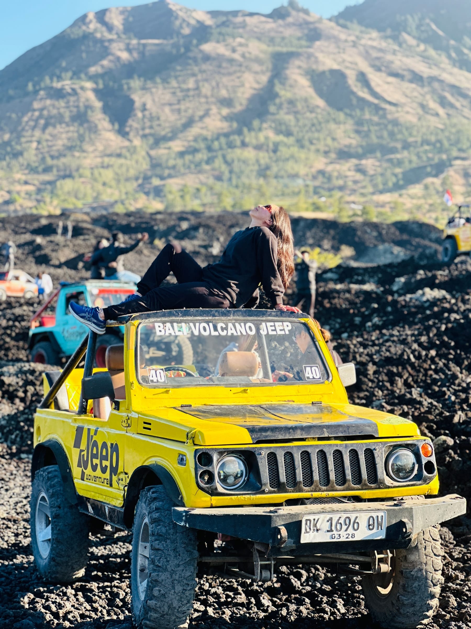 A guest stretched out on a jeep roof in the middle of the black lava field